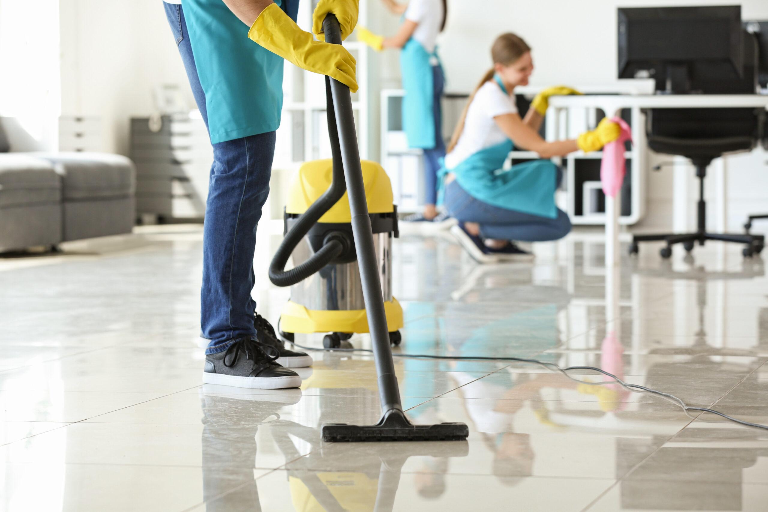 Janitor hoovering floor in office